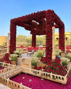 an outdoor seating area with red flowers and greenery