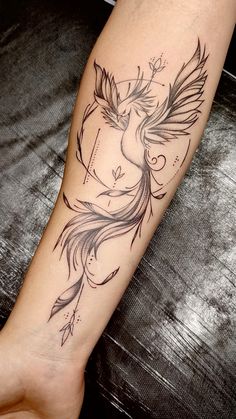 a woman's arm with a bird and arrow tattoo on the left side of her leg