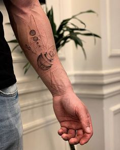 a man with a tattoo on his arm holding an umbrella in front of a potted plant