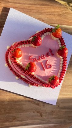 a heart - shaped cake with strawberries on it is sitting on a piece of paper