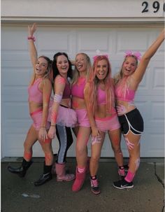 a group of young women in pink outfits posing for a photo with their arms up