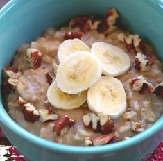 a blue bowl filled with oatmeal topped with bananas and pecans