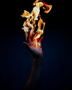 a hand holding out flames in the dark