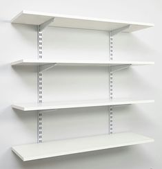 three white shelvings are on the wall in front of each other and one is empty