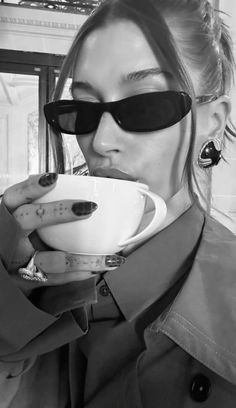 a woman wearing sunglasses drinking from a cup