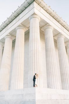 an engaged couple standing on the steps of the lincoln memorial