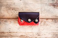 a red and black wallet sitting on top of a wooden table