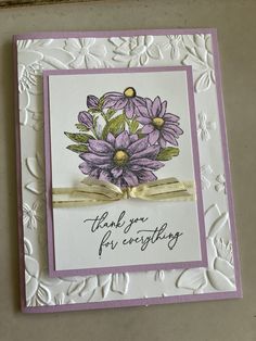 a handmade thank you card with purple flowers and gold ribbon on the bottom corner