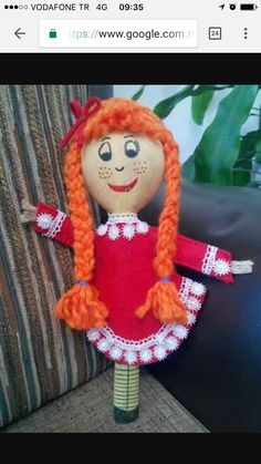 a doll with red hair and braids is sitting next to a couch in a living room