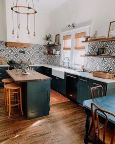 a kitchen with wooden floors and black cabinets, an island in the middle is surrounded by chairs