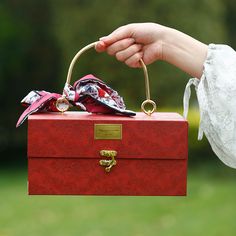 a woman holding a red box with jewelry on it