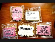 four decorated cookies sitting on top of plastic wrappers with words written on the side