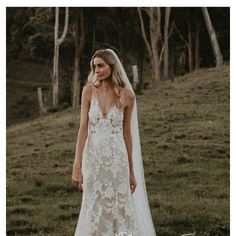 a woman wearing a wedding dress standing in the grass