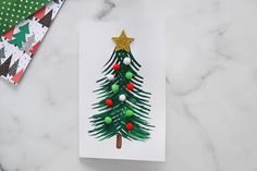 a card with a christmas tree on it next to some wrapping paper and other holiday decorations