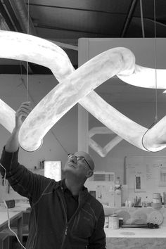 a man is working on some kind of light fixture in a room with lights hanging from the ceiling