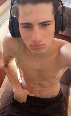 a shirtless man with headphones on sitting in a chair looking at the camera