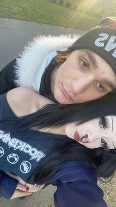 two young people are posing for a photo in front of the camera, one is wearing a beanie and the other has long black hair