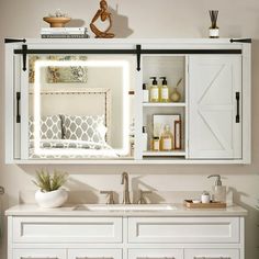 a bathroom with white cabinets and lights above the sink, along with other items on the counter