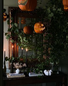 pumpkins are hanging from the ceiling above a mantle with candles and books on it