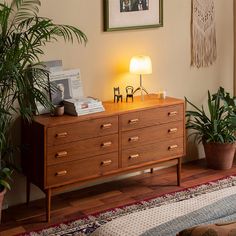 a wooden dresser sitting next to a lamp on top of a table in a living room