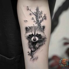 a raccoon tattoo on the arm with leaves and branches around it's neck