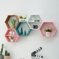 three hexagonal shelves with plants and decorations on them, hanging from the wall