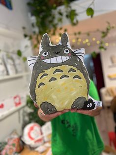 a person holding up a cut out of a totoro