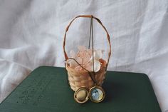 a basket filled with lots of pink flowers sitting on top of a green book next to a pair of binoculars