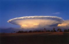 a large cloud in the sky over a field