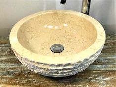 a round stone sink sitting on top of a wooden table