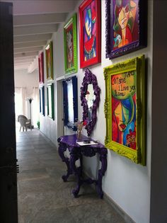 the hallway is decorated with colorful paintings and art on the wall, along with a purple table