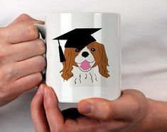 a person holding a coffee mug with a dog wearing a graduation cap