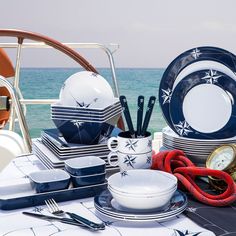 the table is set with plates, bowls and utensils for dinner on the beach