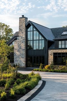 a large black house with lots of windows and landscaping around it's front entrance