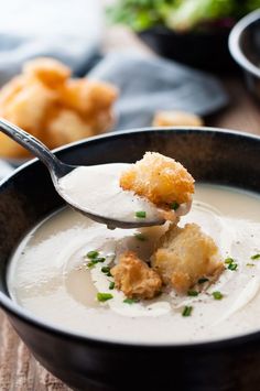 a spoon full of soup with bread croutons on the side and dipping sauce in it