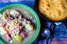 a bowl filled with soup next to a pot of cornbread