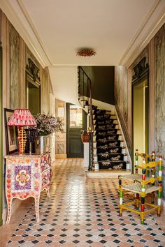 a hallway with stairs and tiled flooring next to a table