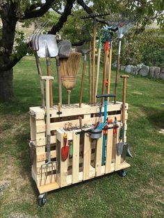 a wooden cart filled with gardening tools on top of a grass covered field next to a tree