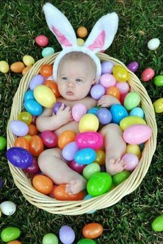 a baby in a basket filled with easter eggs