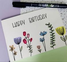 a birthday card with flowers on it next to a marker and some crayons