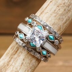 a stack of rings sitting on top of a piece of wood with turquoise and white stones