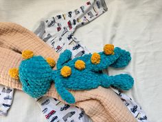 a crocheted stuffed animal laying on top of a bed next to a blanket