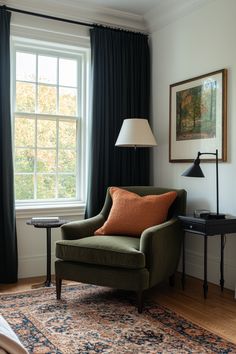 a green chair sitting in front of a window next to a table with a lamp on it