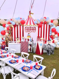 a circus themed birthday party is set up with balloons, plates and cups on the table