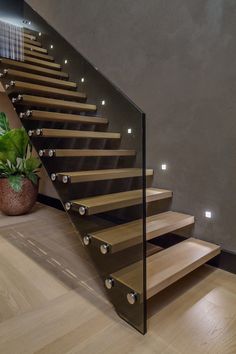 a wooden staircase with glass balustrades and metal handrails in a modern home