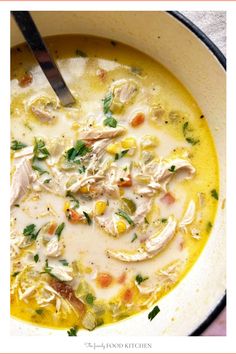 a bowl filled with chicken and corn soup on top of a white table next to a spoon