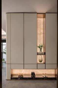 shoes are lined up on the floor in front of a cabinet with flowers and vases