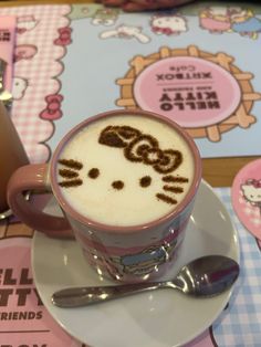 a hello kitty latte on a plate with spoons