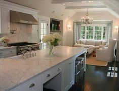 a large kitchen with white cabinets and marble counter tops, along with a center island