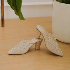 two white shoes sitting on top of a wooden floor next to a potted plant